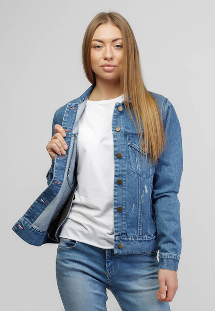 girl in a denim jacket and blue denim pants on a white background. - Фото, изображение