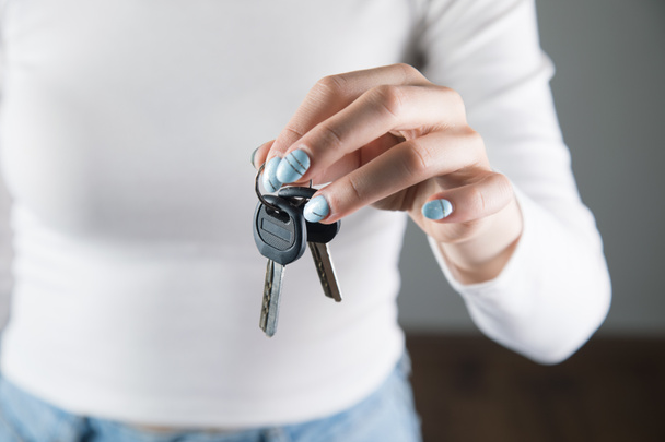 jonge vrouw in wit houdt sleutels - Foto, afbeelding