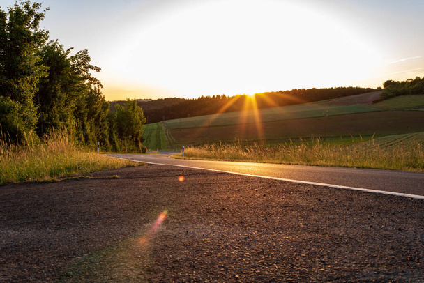 Sunset on asphalt road in countryside in Werbach, Germany - Photo, Image