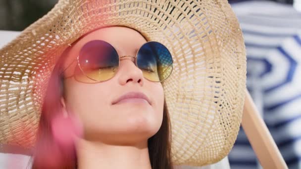Закрыть видео женщины в солнцезащитных очках, расслабляющейся на пляже. Съемка с красной гелиевой камерой в 8K. - Кадры, видео