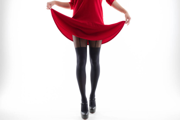 Young woman in red dress and beautiful pantyhose in black shoes on white background - Fotoğraf, Görsel
