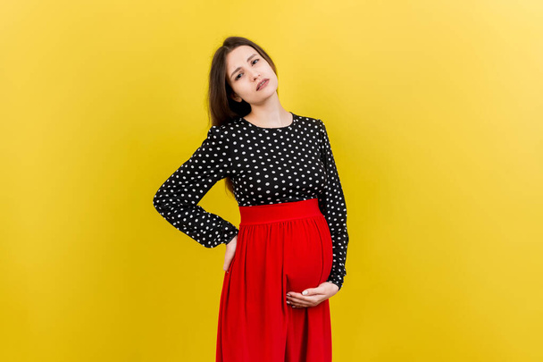 Pregnant woman with a pain in her back on colored Background isolated. - Foto, Bild