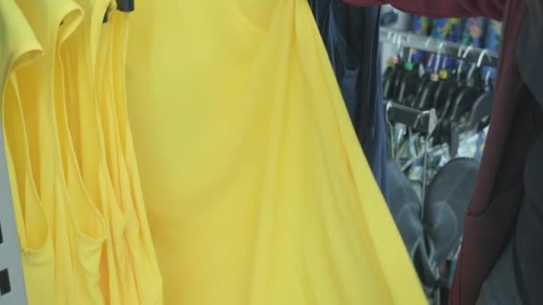 Femme en surpoids choisit une robe jaune spacieuse dans un magasin de vêtements pour acheter - Séquence, vidéo
