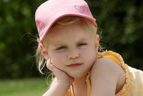Retrato de menina adorável criança em chapéu de verão rosa que estabelece em um prado verde - Foto, Imagem