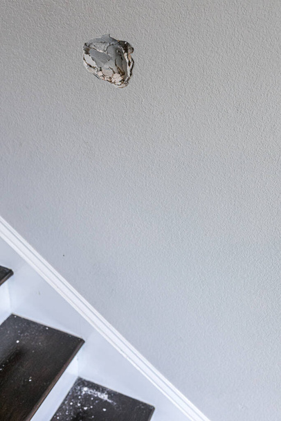 Ein Loch in der Wand eines Treppenhauses, verursacht durch einen Faustschlag durch die Wand - Foto, Bild