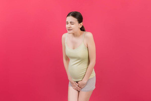 妊娠中の尿失禁.妊娠中の腹痛.色付きの背景についての成熟したヘルスケアの概念. - 写真・画像