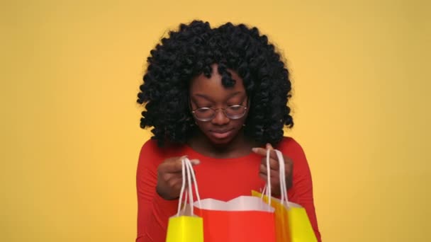 Positive black woman opening shopping bags and saying wow - Filmati, video