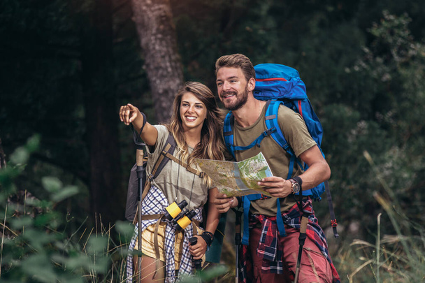 Couple hiking trough forest. Using map to get good direction. - Foto, Imagen
