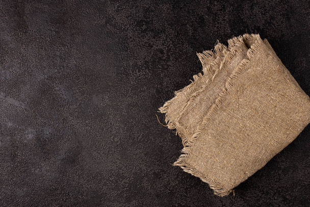 Burlap napkin on a dark structural background, top view. Copyspace - Fotografie, Obrázek
