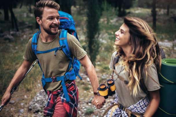 Молодые туристы улыбаются счастливой прогулке в лесу во время кемпинга.  - Фото, изображение
