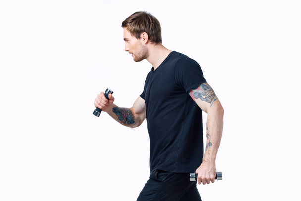 sporty man with dumbbells on white background her tattoo on arm black t-shirt cropped view - Foto, Imagen