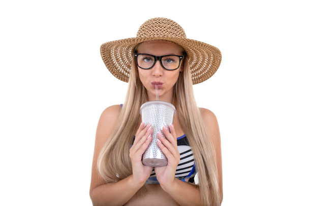 Portrait of a young woman in a blue swimsuit and hat drinking lemonade - Photo, Image