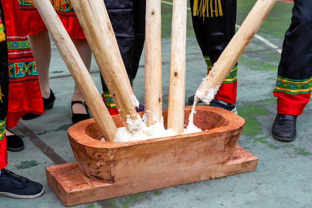 Skupina lidí, kteří kladou lepkavou rýži dřevěnými tyčinkami na výrobu rýžových koláčů s vlastnostmi národnosti Guangxi Zhuang - Fotografie, Obrázek
