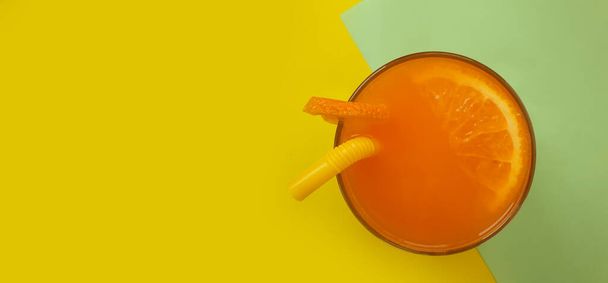 orange juice with a straw on a colored background - Fotoğraf, Görsel