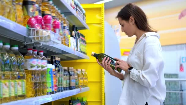 Donna acquirente scegliendo l'olio d'oliva nel negozio - Filmati, video