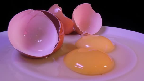 Két törött, nyers tojás kagylóval. Forgó videó. - Felvétel, videó