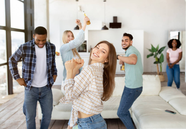Group of millennial diverse friends having party, dancing and drinking beer, enjoying fun weekend together at home - Photo, image