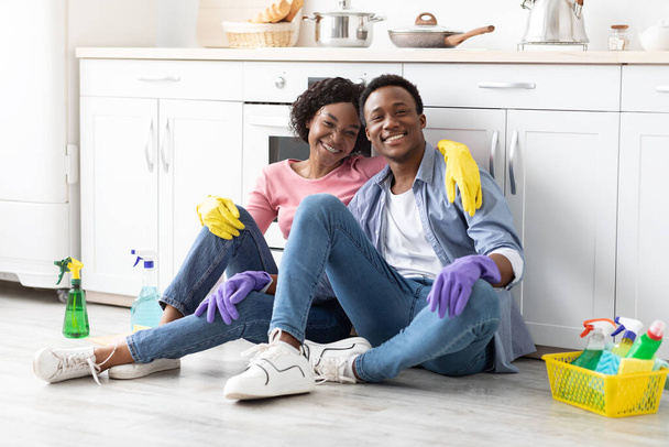 Tired black couple sitting in kitchen, hugging and smiling - Foto, afbeelding