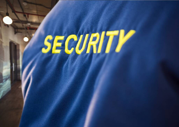 Composition of midsection of security guard blue jacket with yellow text over office background. security and safety concept digitally generated image. - Фото, зображення