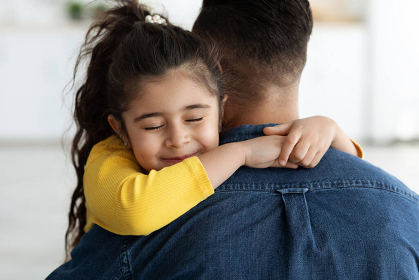 Η Ημέρα των Πατέρων. Χαριτωμένο κορίτσι Άραβας αγκαλιάζει τον πατέρα της στο σπίτι - Φωτογραφία, εικόνα