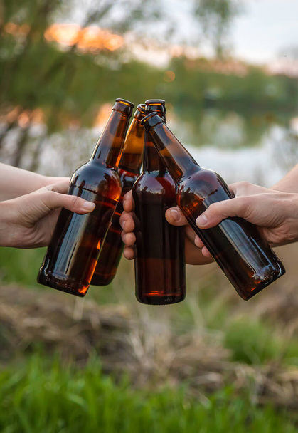 Bottiglie con birra nelle mani dei giovani in natura. Concentrazione selettiva. Natura. - Foto, immagini
