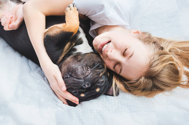 Owner hugs her dog of breed French Bulldog - 写真・画像