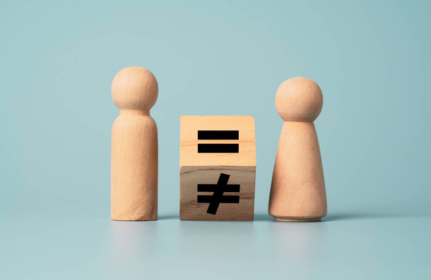 男性と女性の木製の図の間の等しい記号に不平等のフリッピング。人間とビジネスの正しい概念.  - 写真・画像