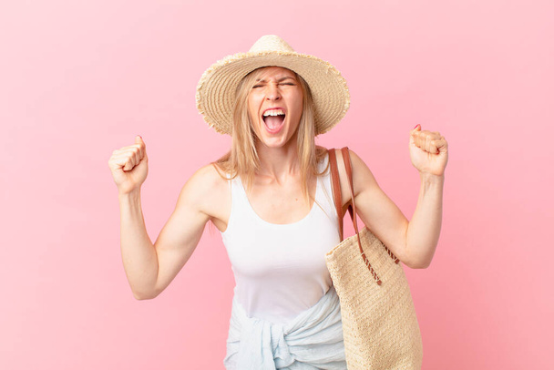young blonde woman shouting aggressively with an angry expression. summer concept - Фото, изображение