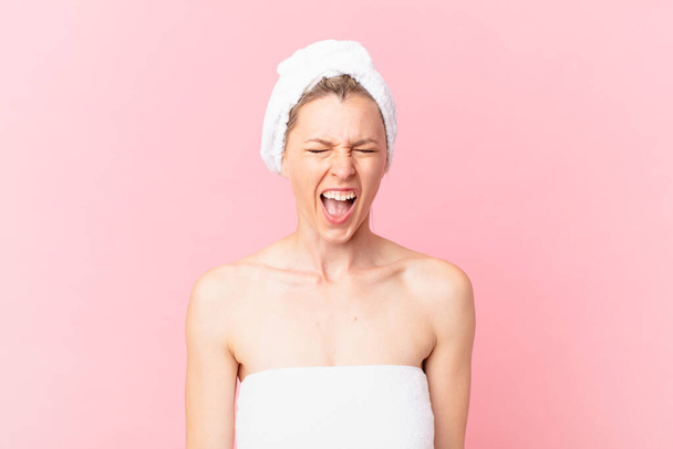young blonde woman shouting aggressively, looking very angry and after shower - Φωτογραφία, εικόνα