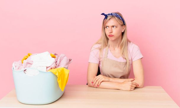 young blonde woman feeling sad, upset or angry and looking to the side. wash clothes concept - 写真・画像