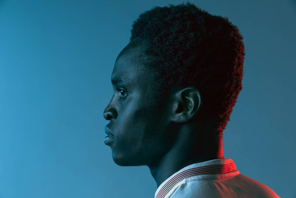 Gros plan Homme africain footballeur isolé sur fond bleu au néon - Photo, image