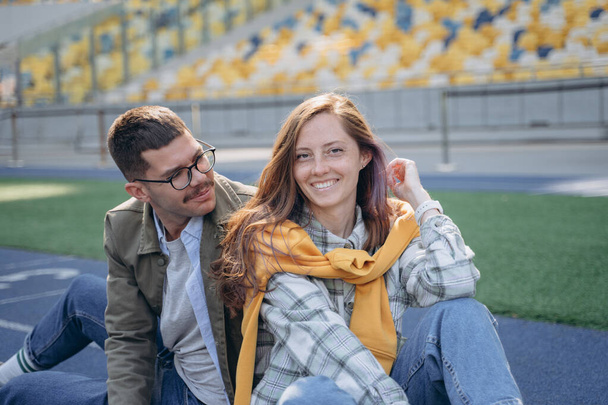 photo of a couple sitting on an empty field stadium - Foto, afbeelding