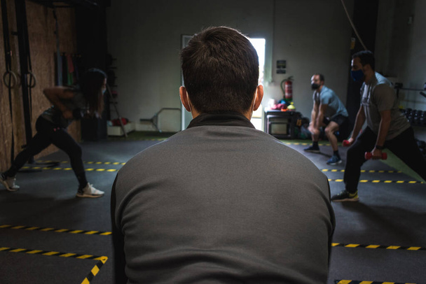 Widok z tyłu osobistego trenera prowadzącego zajęcia fitness w pomieszczeniach - Zdjęcie, obraz