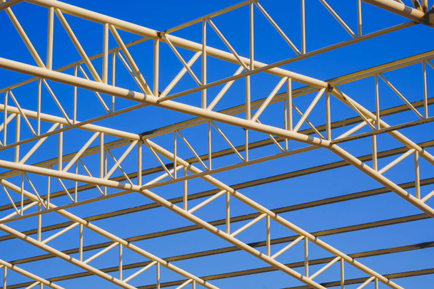 Низький кут зору жовтого металу будівельної конструкції даху в будівельній зоні на фоні блакитного неба
 - Фото, зображення