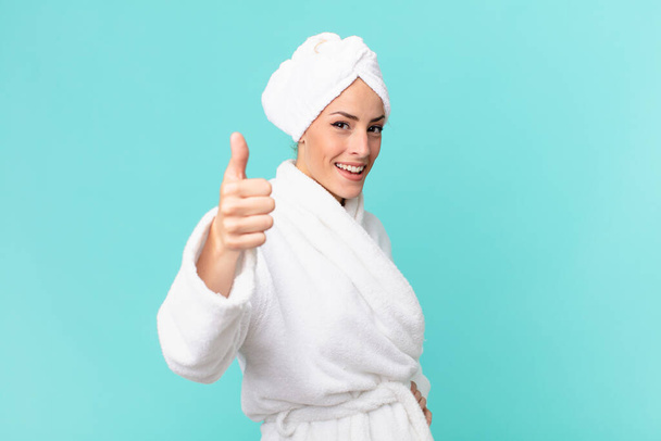 young blonde woman feeling proud,smiling positively with thumbs up. shower concept. - 写真・画像
