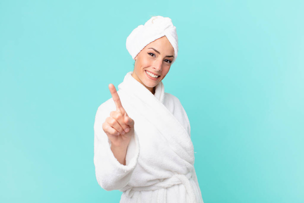 young blonde woman smiling proudly and confidently making number one. shower concept. - 写真・画像