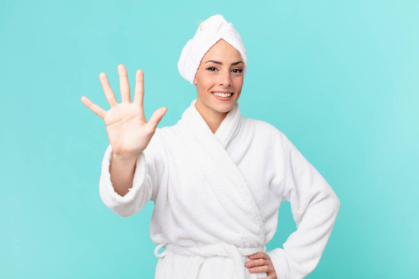 young blonde woman smiling and looking friendly, showing number five. shower concept. - Photo, image