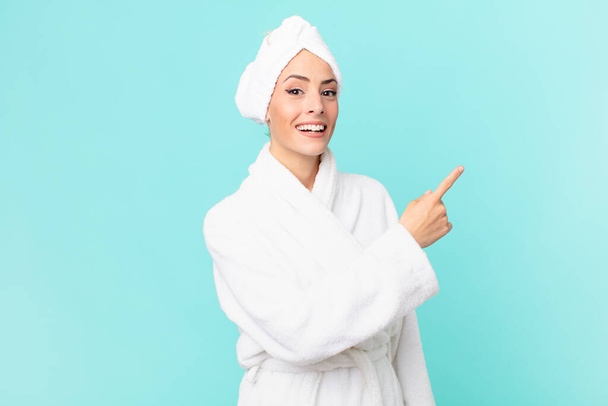 young blonde woman looking excited and surprised pointing to the side. shower concept. - Foto, Imagem