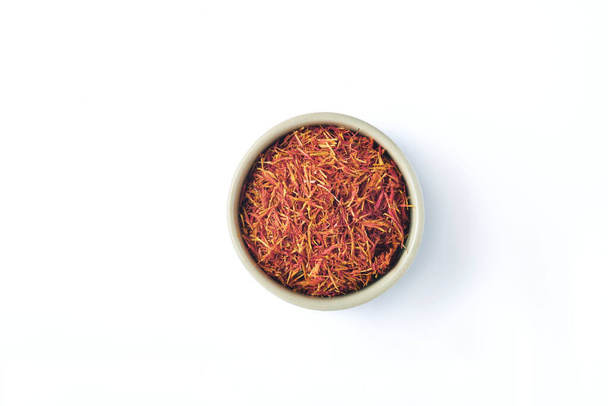 Saffron spices threads in heart shaped plate isolated on white background. Top view. Saffron flavor and coloring seasoning ingredient. - Photo, image