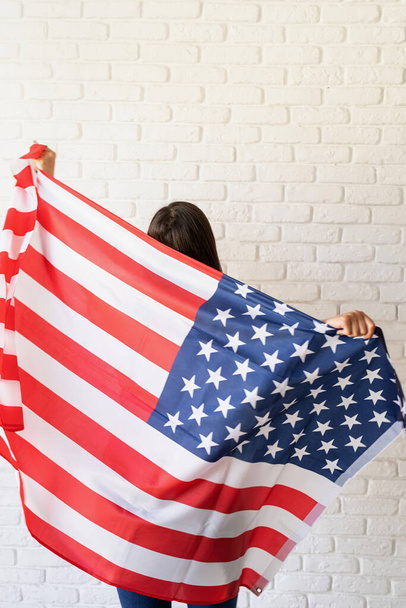 День незалежності США. З 4 липня. Молода посміхається жінка з національним прапором США, задній вид - Фото, зображення