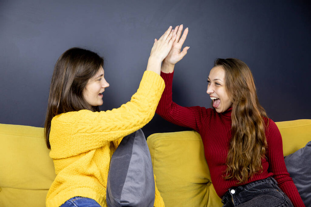 jovem lésbicas casal gestos alta cinco rindo e olhando para o outro - Foto, Imagem