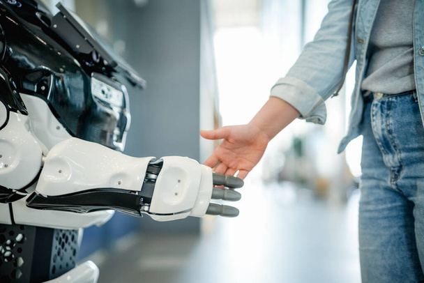 Young woman shaking a modern robot hand - Photo, Image