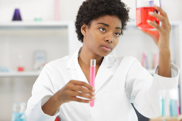 female scientist holding up a beaker to examine the liquid - Foto, afbeelding
