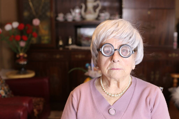 zblízka portrét dospělé ženy s kulatými brýlemi doma - Fotografie, Obrázek