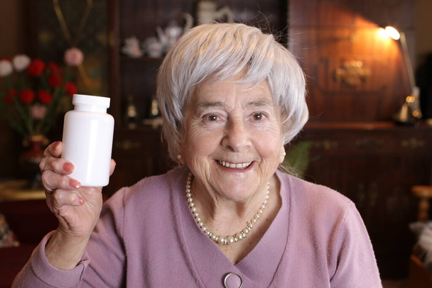 close-up retrato de mulher madura segurando frasco de pílulas em casa - Foto, Imagem