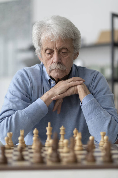 Elderly man playing chess, he is exercising his memory - Foto, afbeelding