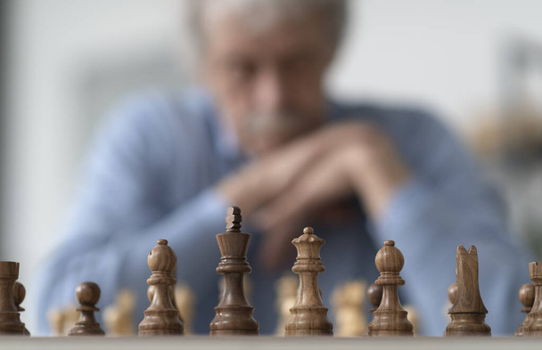 Elderly man playing chess, he is exercising his memory - Foto, Imagen