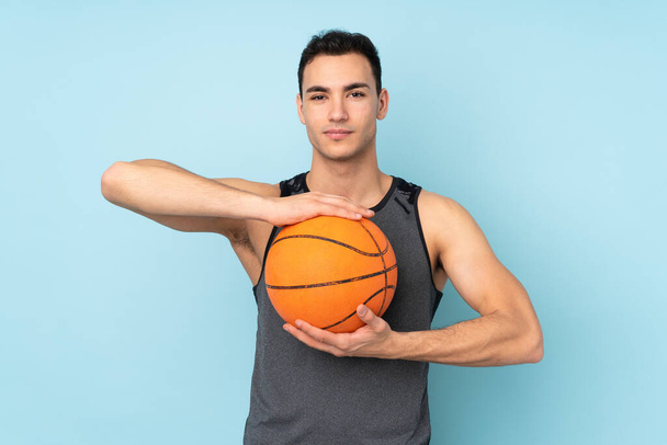 Мужчина на изолированном синем фоне играет в баскетбол - Фото, изображение