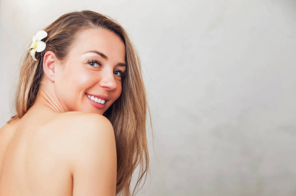 Portrait of young pretty half naked woman with flower for ads beauty spa or massage salon. Portrait of smiling young topless female middle aged old on gray background. Health, youth and beauty concept - Φωτογραφία, εικόνα