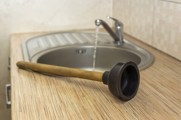 Бытовой сантехнический инструмент для очистки засоров вантуз на кухне раковины - Фото, изображение